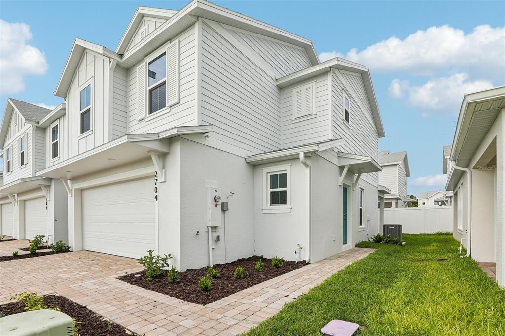 A two-story townhouse with a white stucco and siding exterior, a garage, and a walkway — 2704 MEADOW CREST DRIVE, ST CLOUD, FL