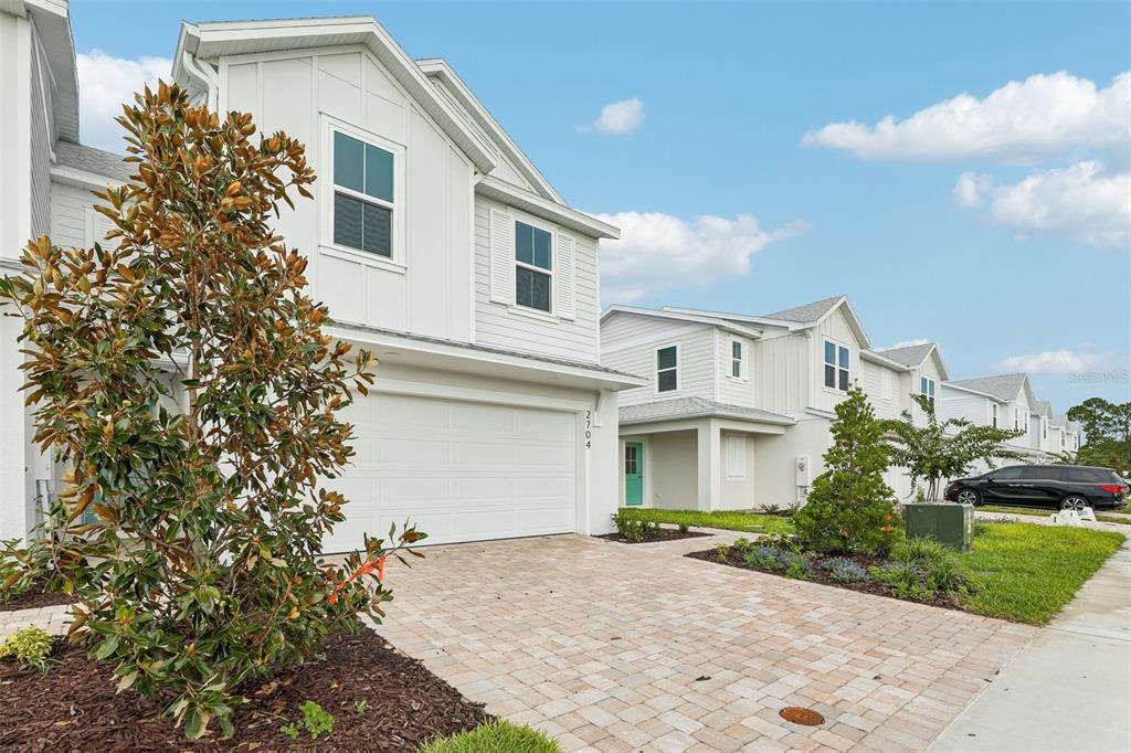 A two-story white townhouse with a paved driveway and a front-facing garage — 2704 MEADOW CREST DRIVE, ST CLOUD, FL