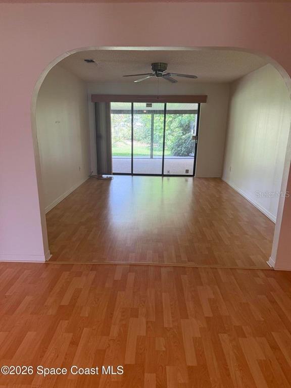 An arched doorway leads to a room with wood-look flooring and sliding glass patio doors — 3079 SEA GATE CIRCLE, MERRITT ISLAND, FL