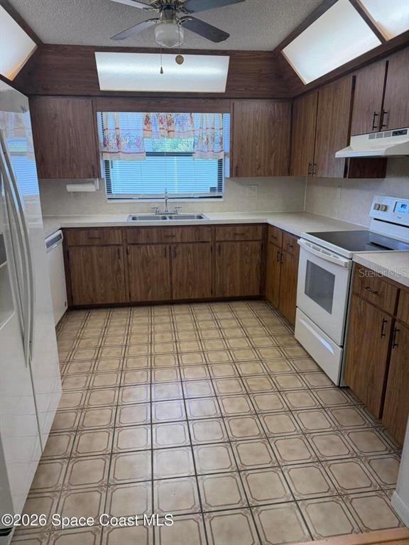 A kitchen features wood cabinets, white countertops, a tiled floor, and a ceiling fan — 3079 SEA GATE CIRCLE, MERRITT ISLAND, FL