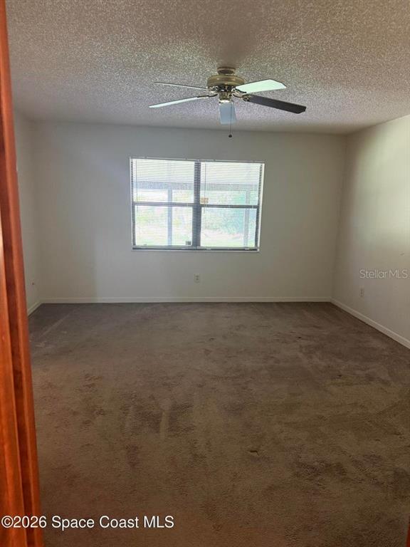 An empty bedroom features beige carpeting, white walls, a ceiling fan, and a single window — 3079 SEA GATE CIRCLE, MERRITT ISLAND, FL
