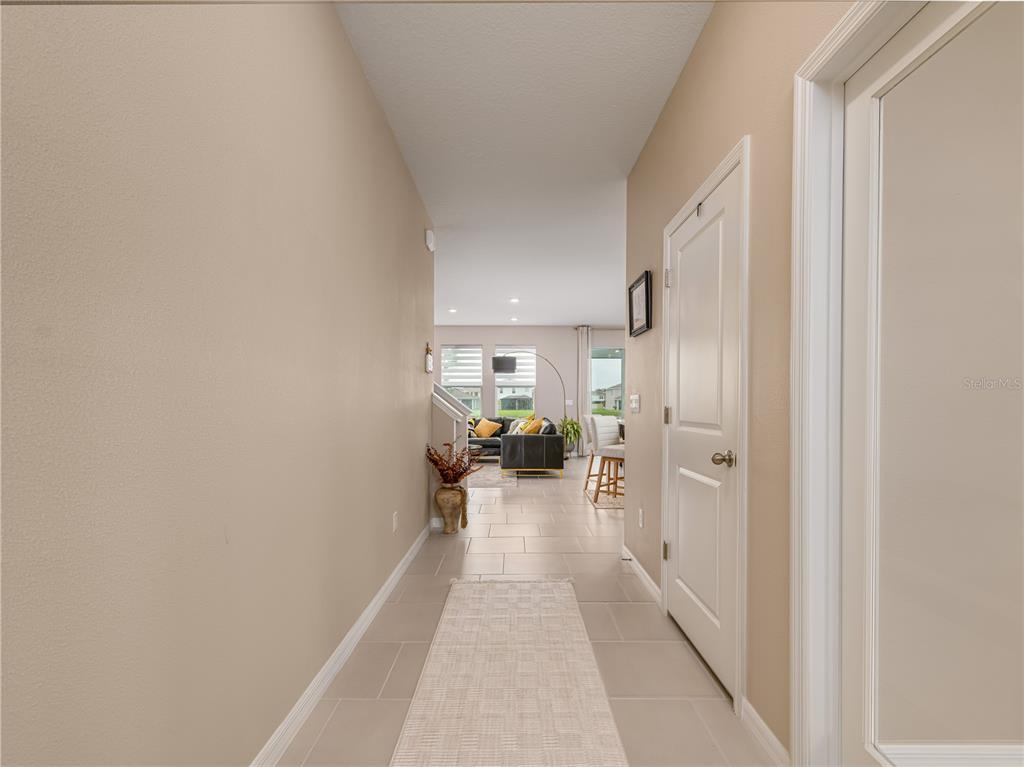 A modern kitchen features granite countertops, white cabinetry, and stainless steel appliances overlooking a living area — 33634 GARDEN SAGE ISLE, WESLEY CHAPEL, FL