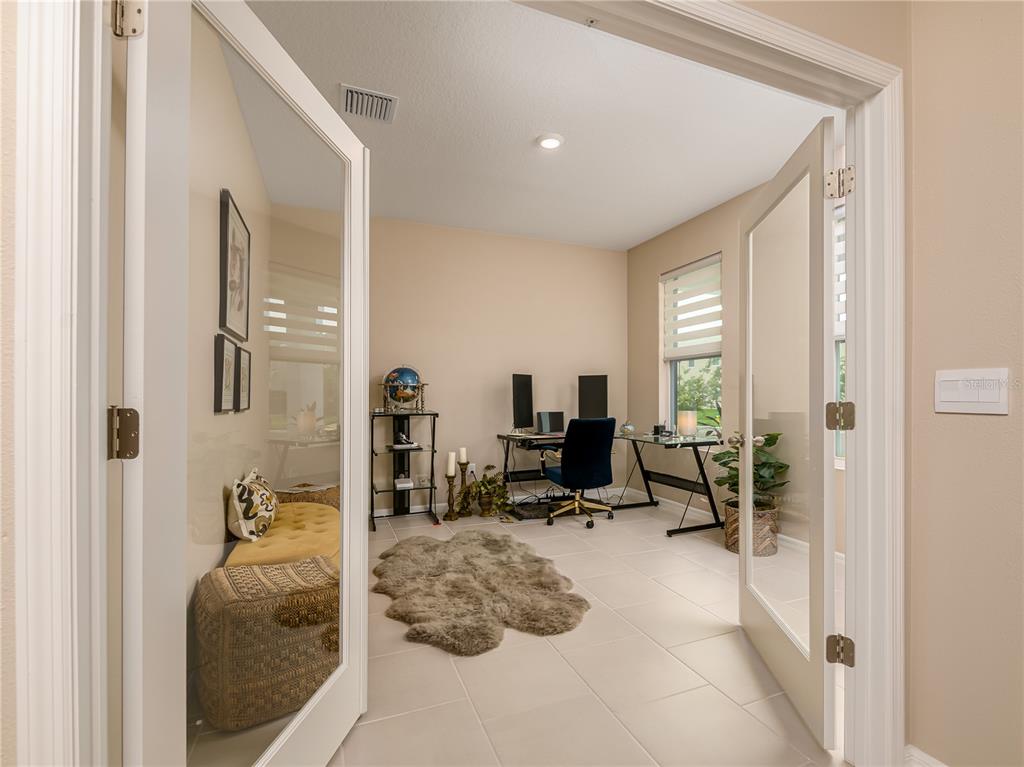 An open-concept living room and kitchen feature a black sectional sofa and white cabinetry — 33634 GARDEN SAGE ISLE, WESLEY CHAPEL, FL