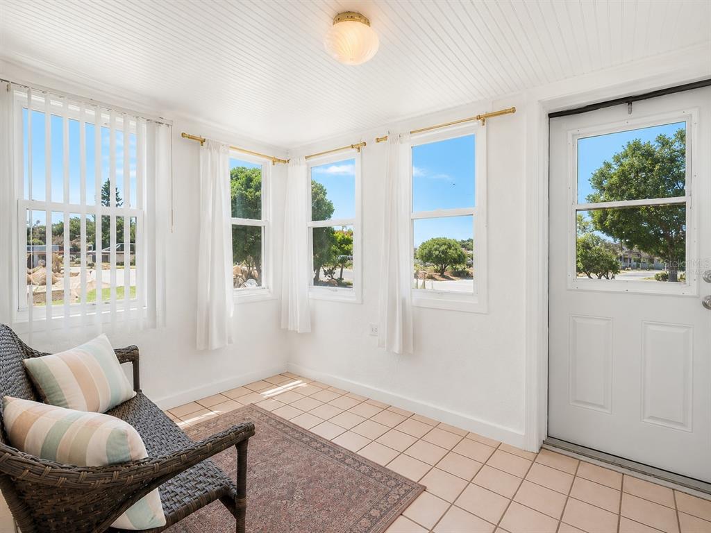 A sunroom with white walls, tiled floors, a wicker chair, and several windows — 151 HOLLAND ROAD, ORMOND BEACH, FL