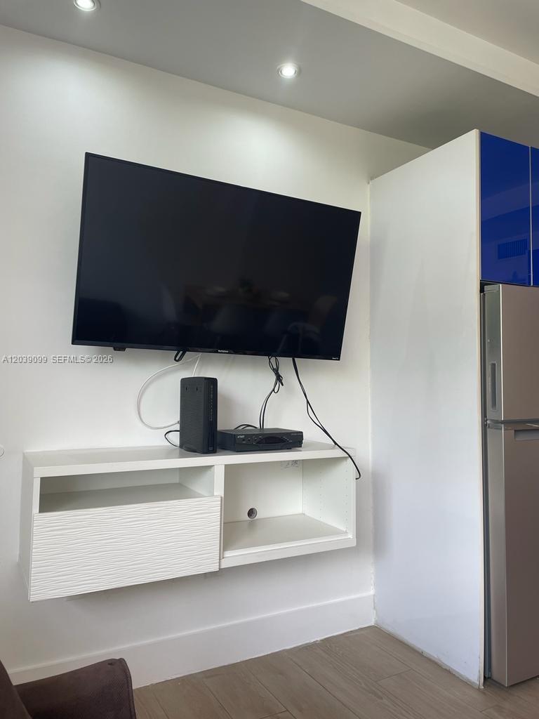 A wall-mounted television sits above a white floating console in a room with light flooring — 700 16th St # 108, Miami Beach FL 33139, MIAMI BEACH, FL