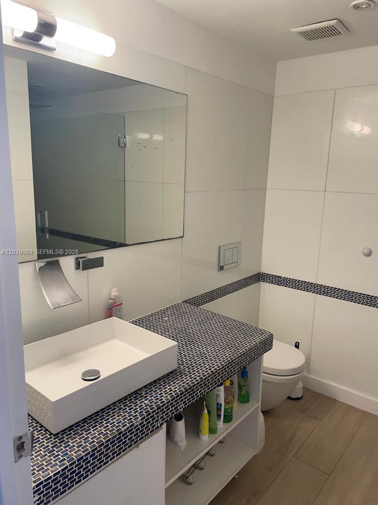 A bathroom features a vessel sink, a tiled countertop, and a wall-mounted mirror — 700 16th St # 108, Miami Beach FL 33139, MIAMI BEACH, FL