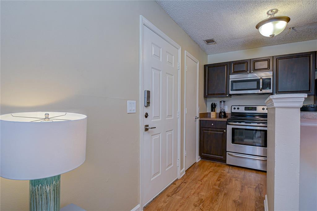 A kitchen with dark wood cabinets, stainless steel appliances, and wood-look flooring — 11901 4TH STREET N UNIT 4206, ST PETERSBURG, FL