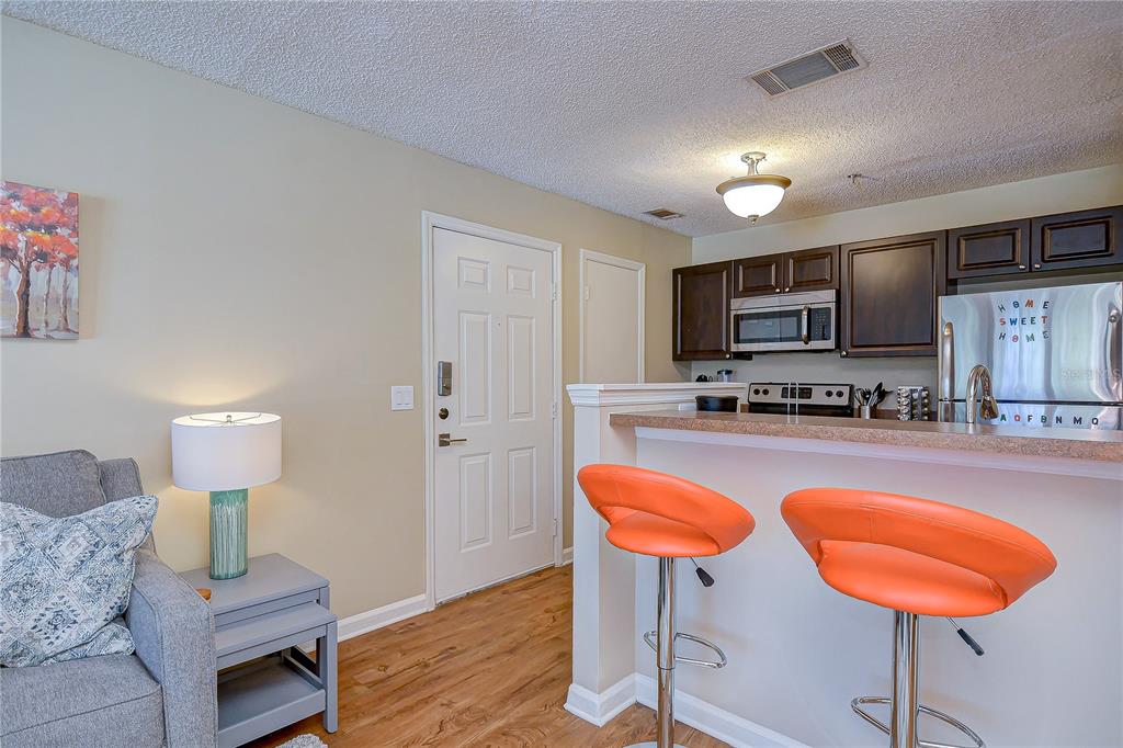 A kitchen with dark cabinets and a breakfast bar overlooks a living area — 11901 4TH STREET N UNIT 4206, ST PETERSBURG, FL