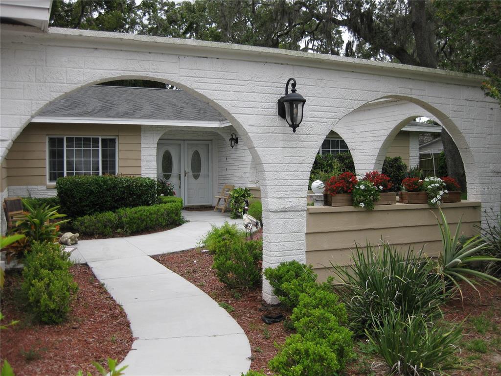 A white brick arched entryway leads to a front door with a concrete walkway — 7026 LENAPE CIRCLE, NEW PORT RICHEY, FL