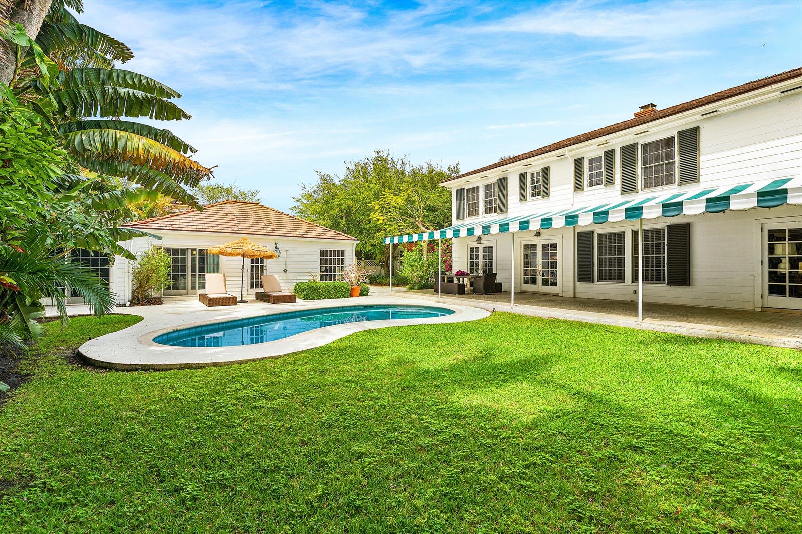 A backyard features a swimming pool, a grassy lawn, and a two-story white house — 210 Merrain Road, Palm Beach FL 33480, PALM BEACH, FL