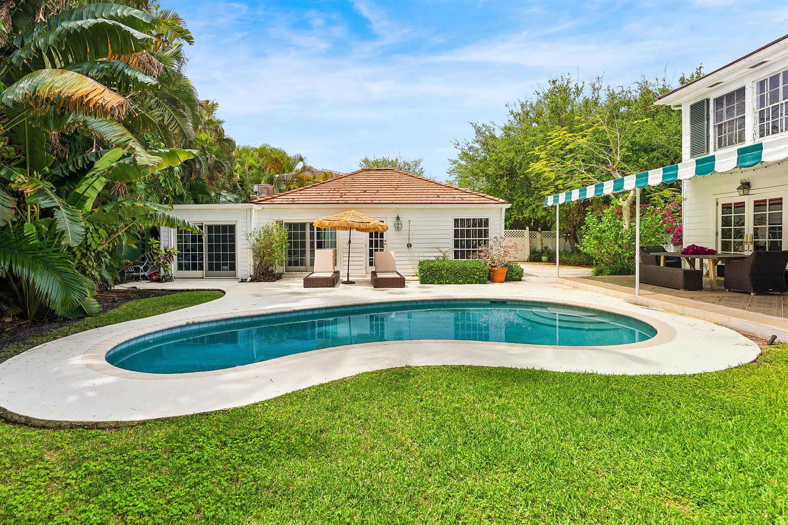 A backyard features a kidney-shaped swimming pool, a white house, and a grassy lawn — 210 Merrain Road, Palm Beach FL 33480, PALM BEACH, FL