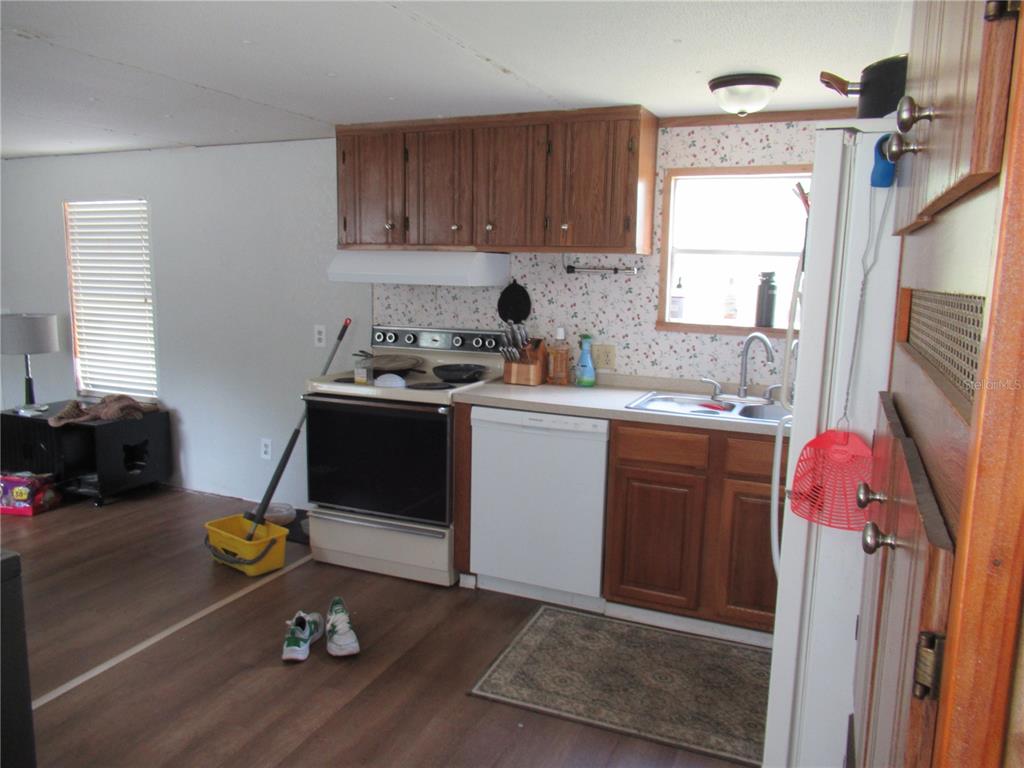 A kitchen features wood cabinets, white appliances, a floral backsplash, and wood-look flooring — 7814 TURKEY CREEK ROAD, PLANT CITY, FL