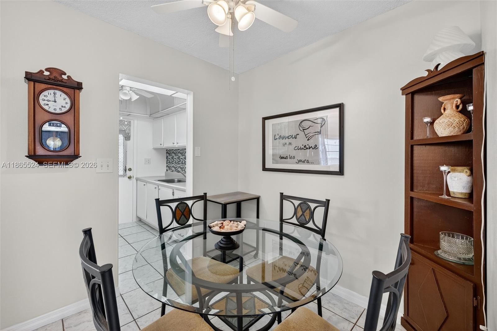 A dining area features a glass-topped table, four chairs, a wall clock, and a wooden bookshelf — 16901 NE 13th Ave # 210, Miami FL 33162, MIAMI, FL