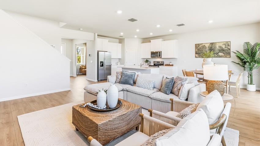 An open-concept living room and kitchen feature light wood flooring, neutral furniture, and recessed lighting — 2827 FISHERY COURT, LAKEWOOD RANCH, FL