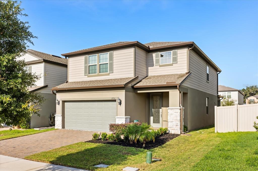 A two-story house with a beige exterior, a two-car garage, and a paved driveway — 2716 VISTA VERDE LANE, KISSIMMEE, FL