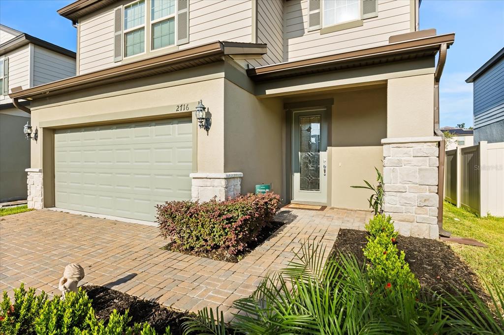 A two-story house exterior features a paved driveway, a garage, and a stone-accented entryway — 2716 VISTA VERDE LANE, KISSIMMEE, FL