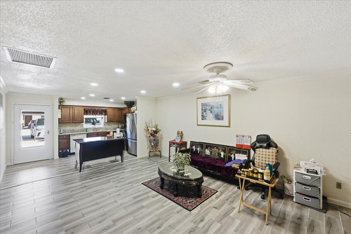 An open-concept living area features light wood-look tile flooring, a kitchen island, and a ceiling fan — 6531 SE Federal Highway SE # Q108, Stuart FL 34997, STUART, FL
