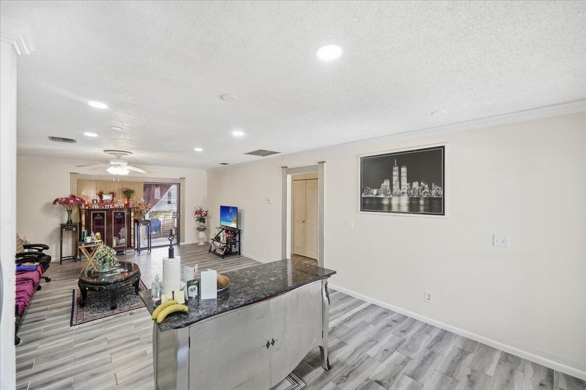 A living room with gray wood-look flooring, a granite-topped island, and a city skyline print — 6531 SE Federal Highway SE # Q108, Stuart FL 34997, STUART, FL