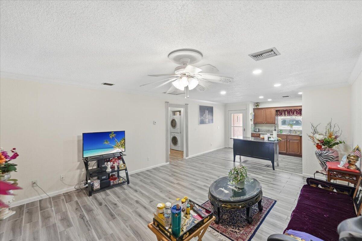 A living room with light wood-look flooring, a ceiling fan, and an open kitchen area — 6531 SE Federal Highway SE # Q108, Stuart FL 34997, STUART, FL