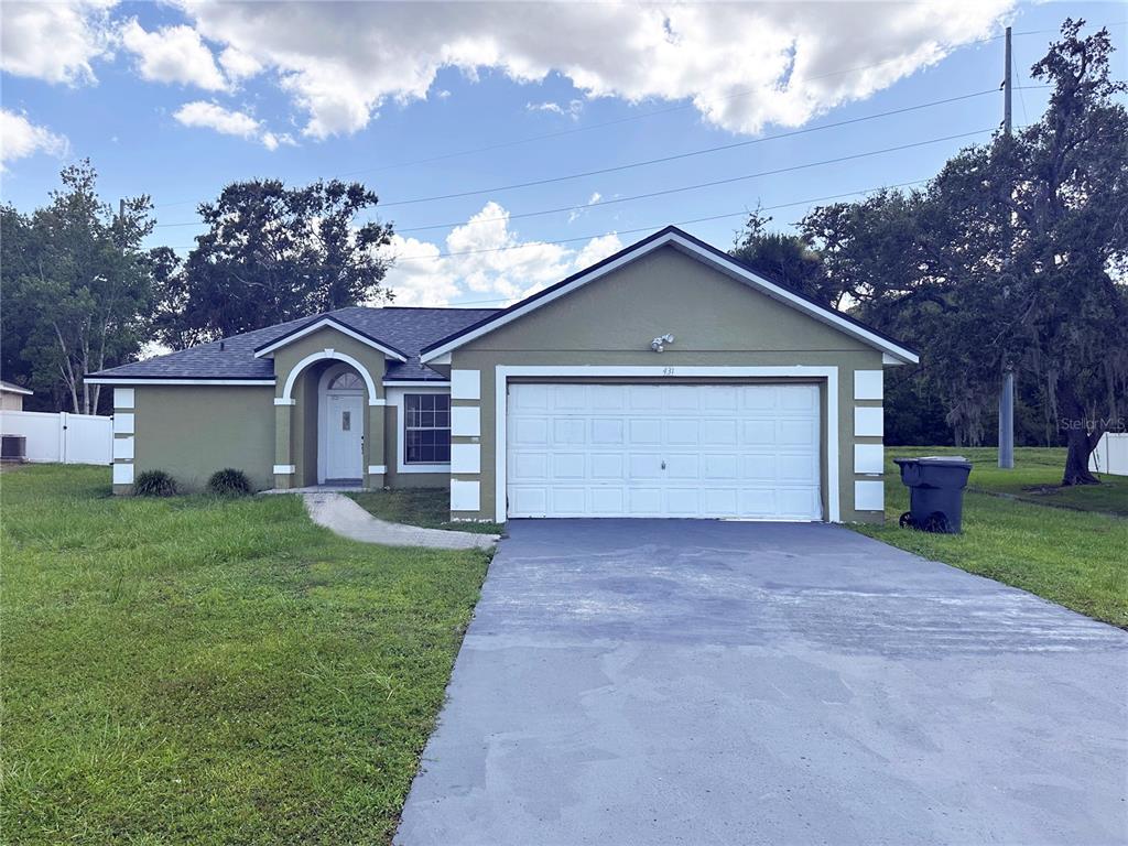 A single-story house with a green stucco exterior, white trim, and a two-car garage — 431 EAGLE DRIVE, POINCIANA, FL