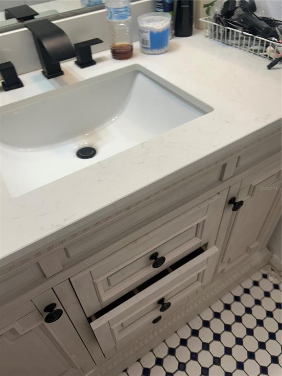 A bathroom vanity features a white countertop, a rectangular sink, and black hardware — 431 EAGLE DRIVE, POINCIANA, FL