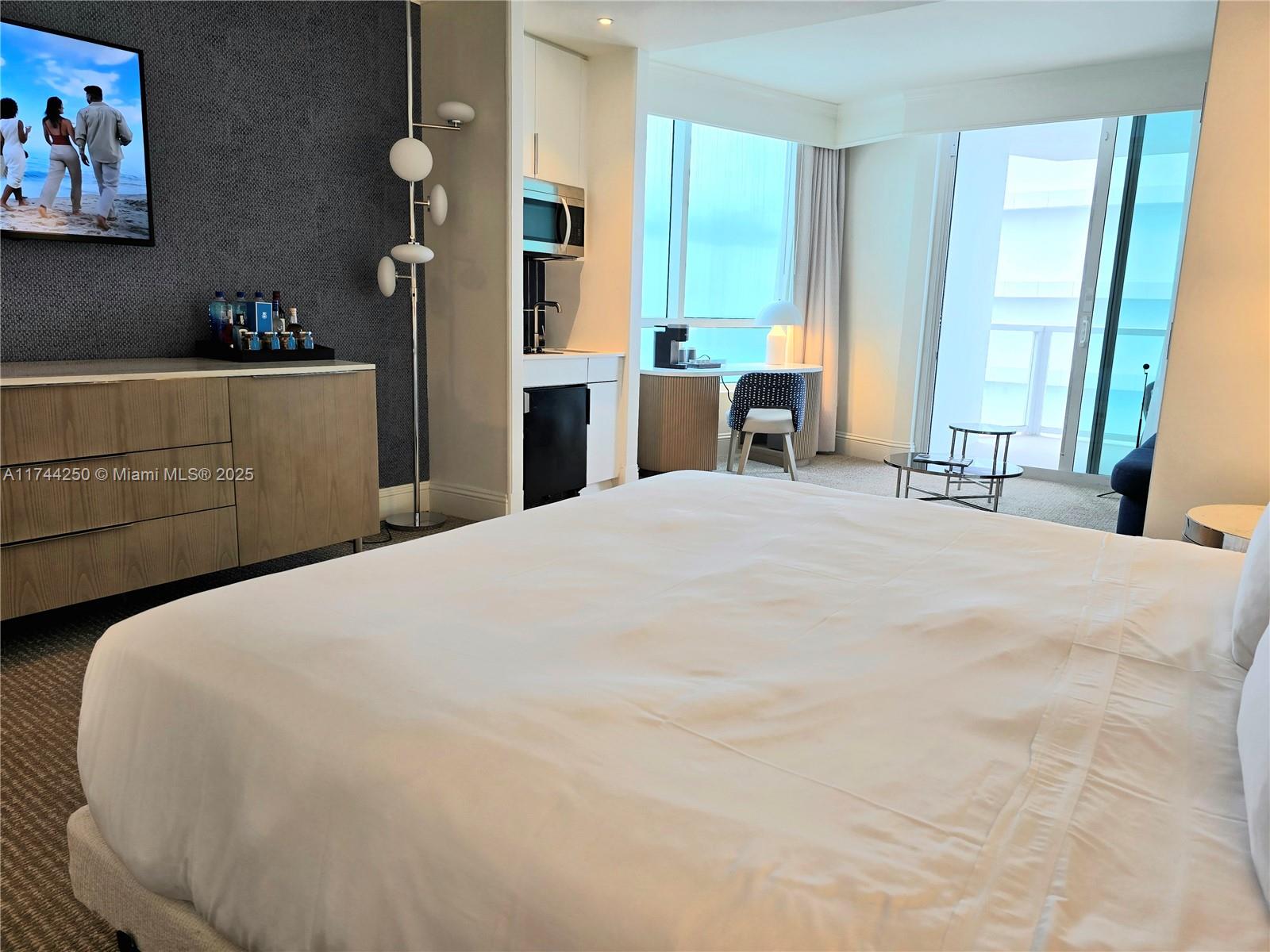 A hotel room features a king bed, a blue sofa, and a balcony with ocean views — 4401 Collins Ave # 1401, Miami Beach FL 33140, MIAMI BEACH, FL