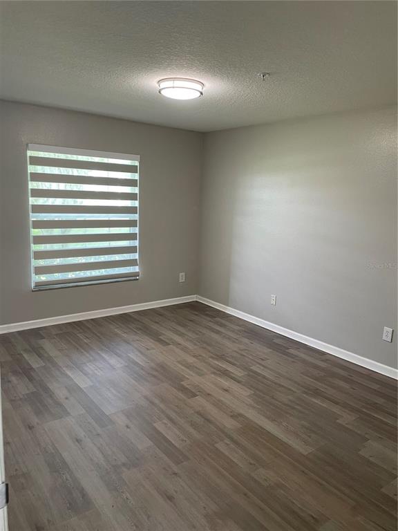 An empty room features light gray walls, wood-look flooring, a window with striped blinds, and a ceiling light — 3960 SOUTHPOINTE DRIVE UNIT 507, ORLANDO, FL