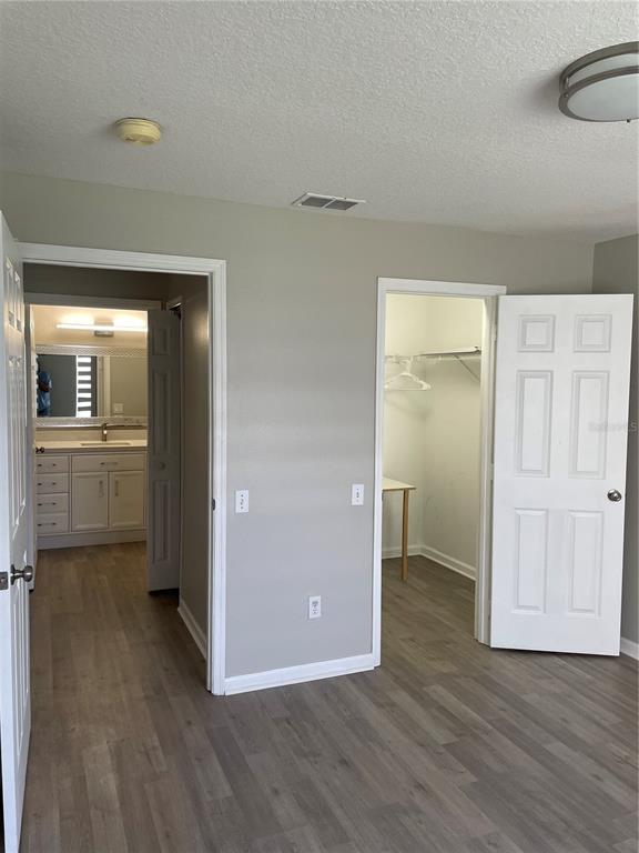 A bedroom with wood-look flooring, a bathroom entrance, and an open walk-in closet — 3960 SOUTHPOINTE DRIVE UNIT 507, ORLANDO, FL