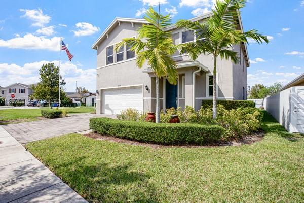 A two-story house with a beige exterior, a paved driveway, and two palm trees — 13235 SW 270th Ter, Homestead FL 33032, HOMESTEAD, FL