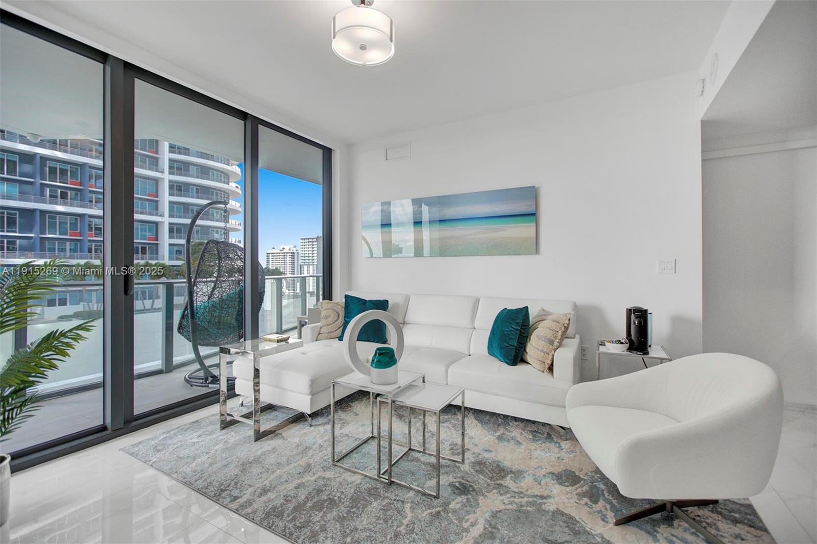 A modern living room features a white sofa, a matching armchair, and a balcony view — 1300 S Miami Ave # 1407, Miami FL 33130, MIAMI, FL