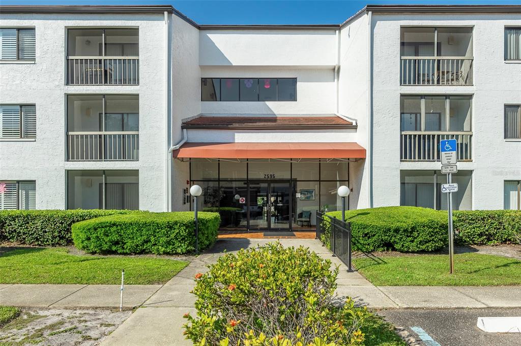 A three-story white apartment building with a central entrance and a red awning — 2595 COUNTRYSIDE BOULEVARD UNIT 8311, CLEARWATER, FL