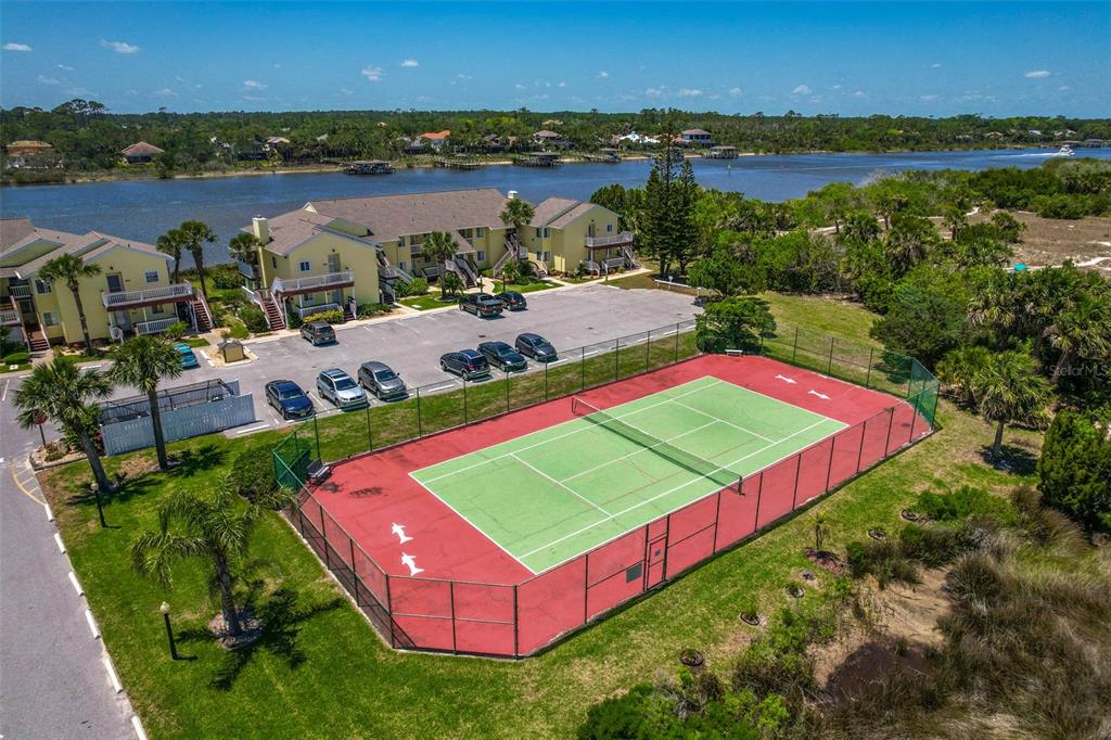 An aerial view shows a tennis court next to a parking lot and apartment buildings — 1003 OCEAN MARINA DRIVE UNIT 1003, FLAGLER BEACH, FL