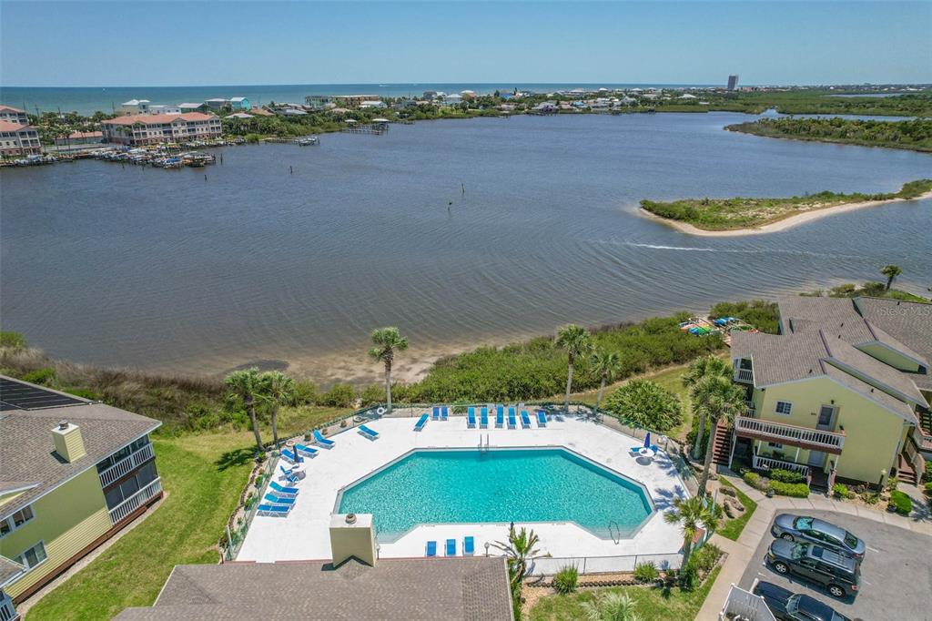 An aerial view of a swimming pool overlooking a bay with nearby residential buildings — 1003 OCEAN MARINA DRIVE UNIT 1003, FLAGLER BEACH, FL