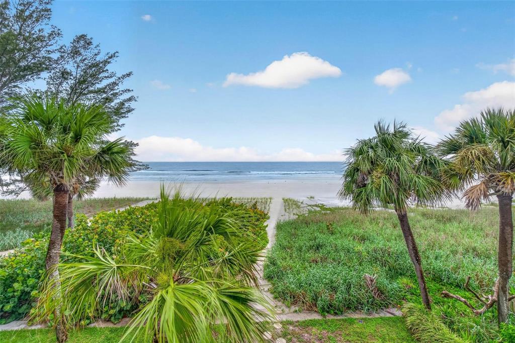 A view of a sandy beach and ocean framed by palm trees and coastal vegetation — 300 BEACH TRAIL UNIT 201, INDIAN ROCKS BEACH, FL