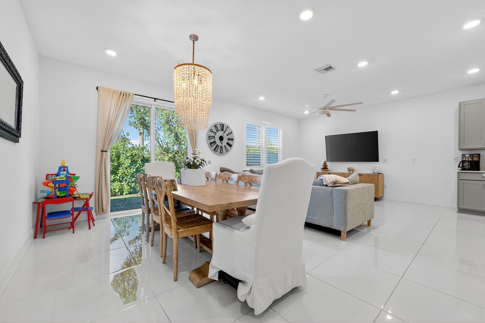 A dining and living area features white tile floors, a wooden table, and a chandelier — 205 Preserve Trail S # 602, Stuart FL 34994, STUART, FL