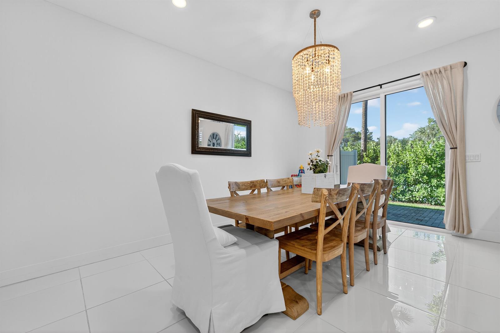 A dining room features a wooden table, cross-back chairs, a beaded chandelier, and sliding doors — 205 Preserve Trail S # 602, Stuart FL 34994, STUART, FL