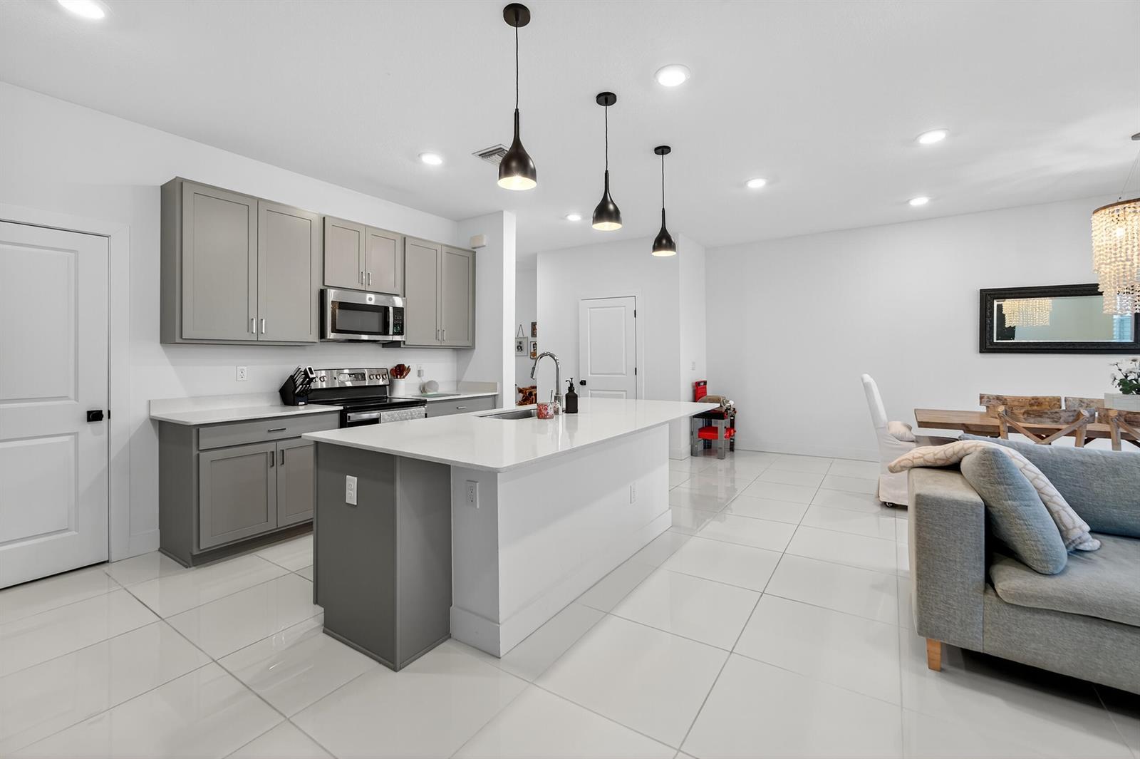 A modern kitchen features gray cabinets, a white quartz island, and tile flooring — 205 Preserve Trail S # 602, Stuart FL 34994, STUART, FL