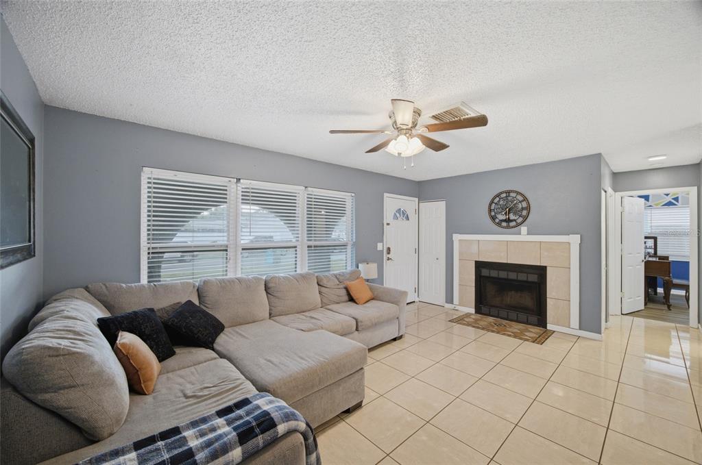 A living room features a large gray sectional sofa, tile flooring, and a stone fireplace — 7941 SMOKETREE COURT, LARGO, FL