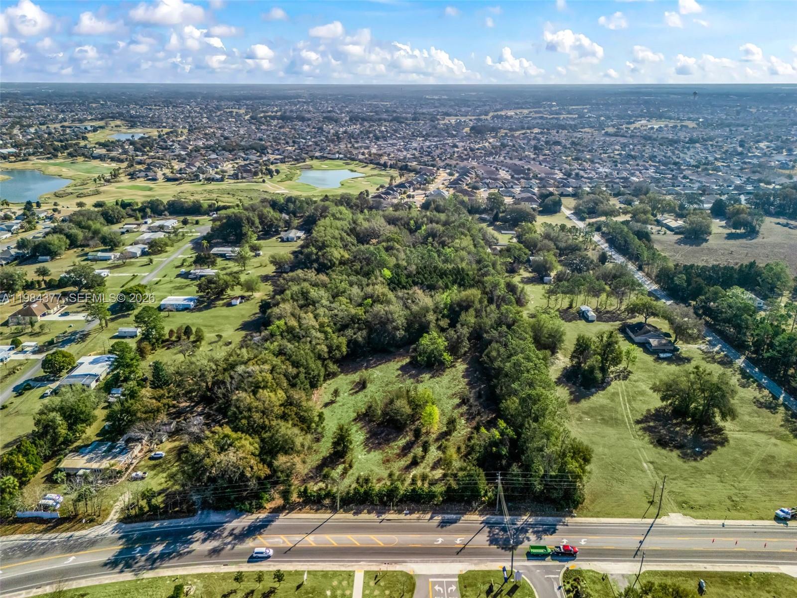 An aerial view shows a vacant, wooded lot situated along a paved road — 4942 E County Road 462, Wildwood FL 34785, WILDWOOD, FL