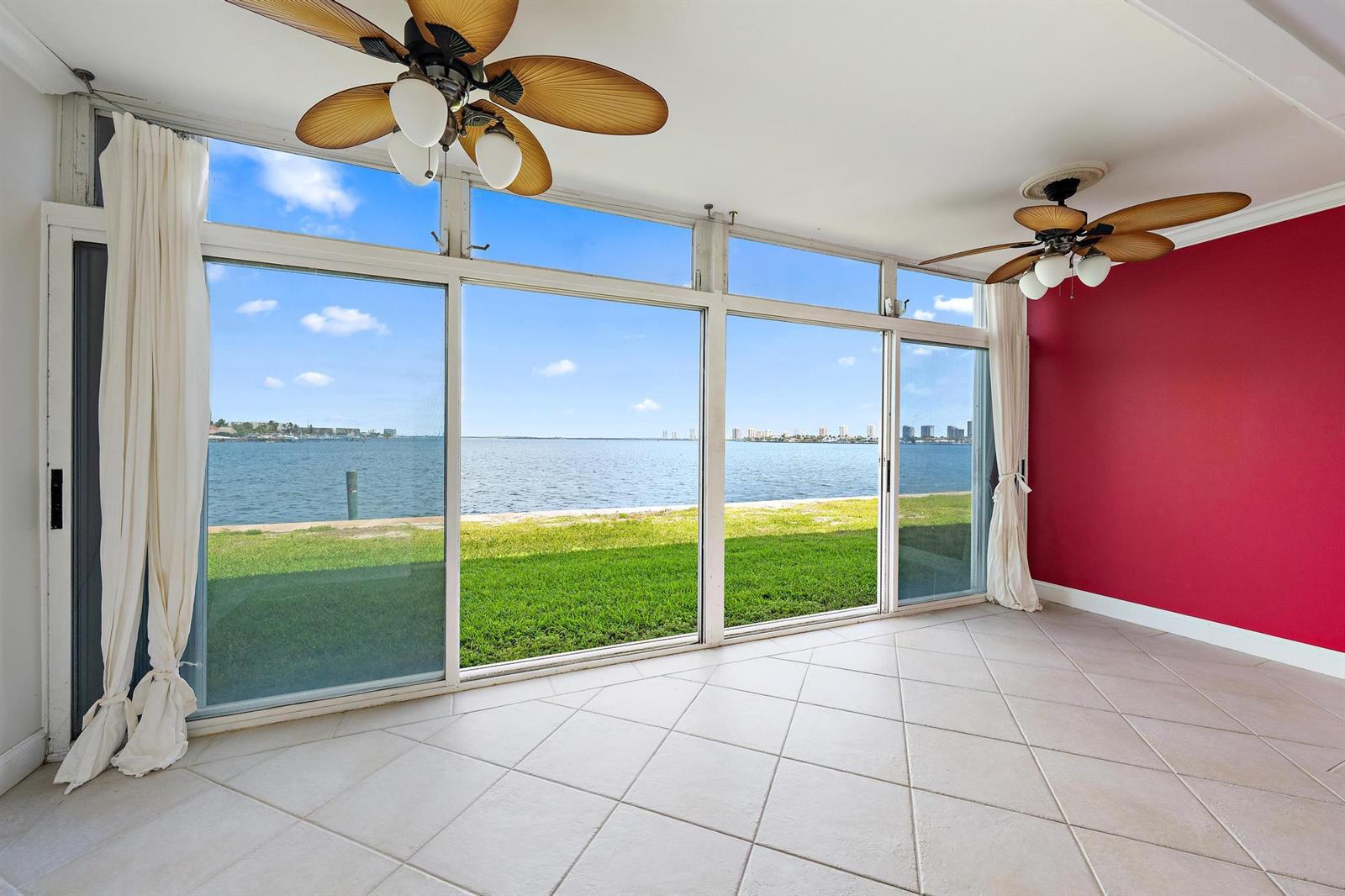 A sunroom with tile floors, two ceiling fans, and large windows overlooking a bay — 400 Wilma Circle # 108, Riviera Beach FL 33404, RIVIERA BEACH, FL