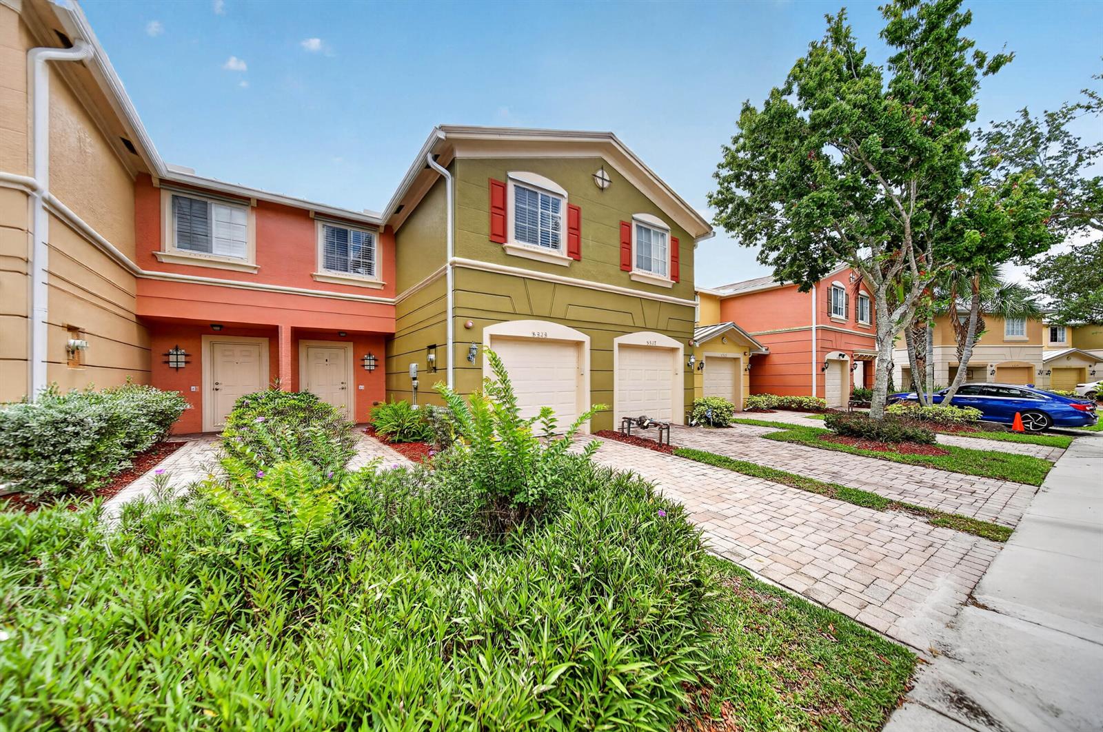 A row of colorful two-story townhouses with attached garages and paved driveways under a blue sky — 5313 SE Jennings Lane, Stuart FL 34997, STUART, FL