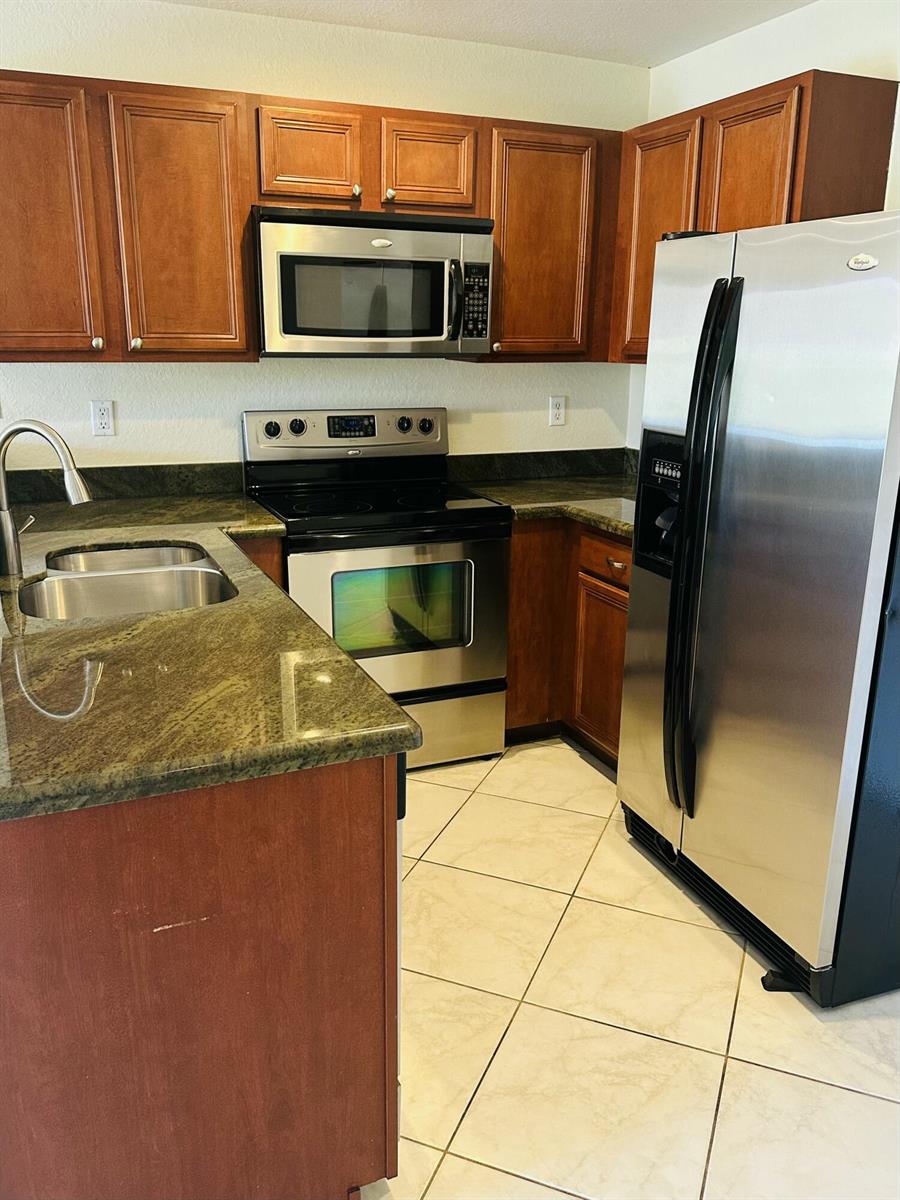 A kitchen features wood cabinets, stainless steel appliances, and green granite countertops — 5313 SE Jennings Lane, Stuart FL 34997, STUART, FL