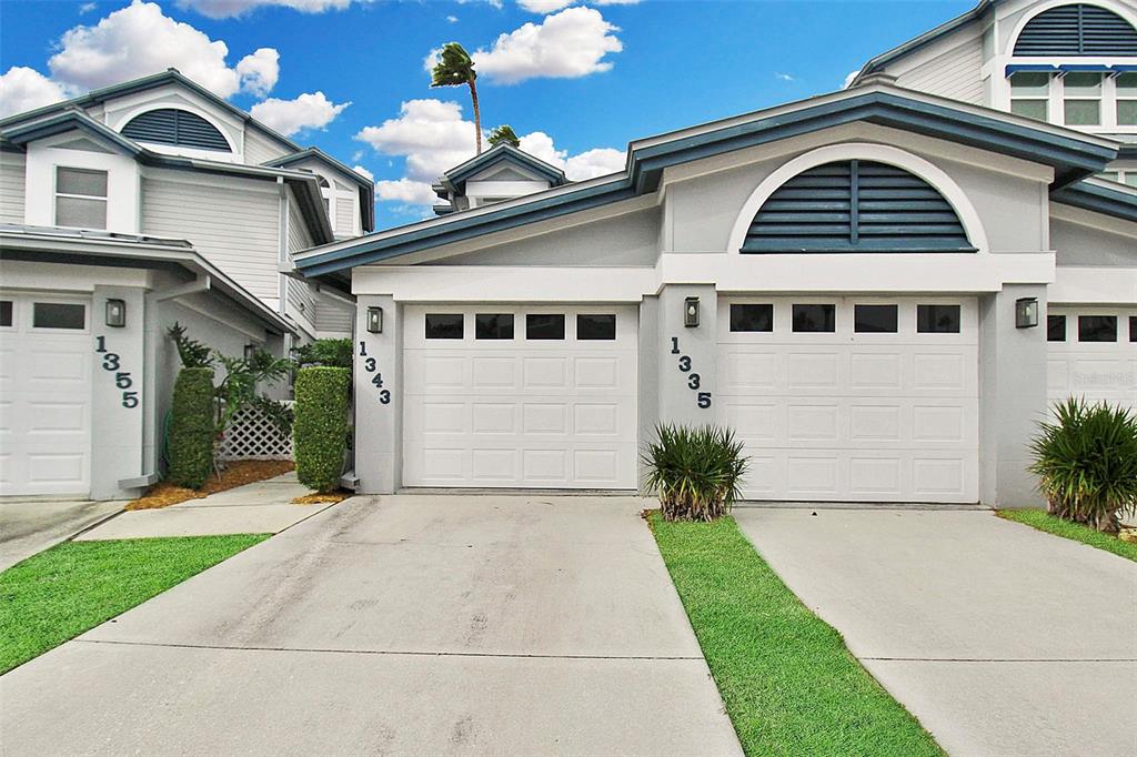 The exterior of two attached townhomes features white garage doors, grey siding, and arched windows — 1343 SIESTA BAYSIDE DRIVE UNIT 1343-C, SARASOTA, FL