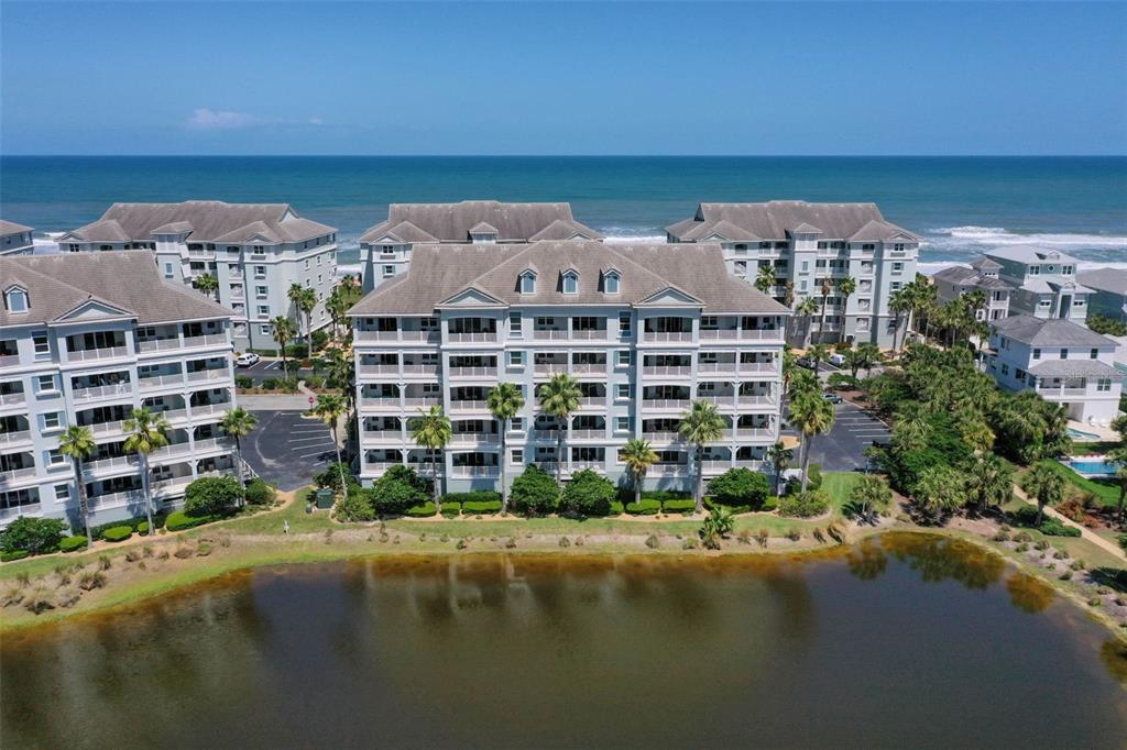 An aerial view shows multi-story apartment buildings situated between a lake and the ocean — 1000 CINNAMON BEACH WAY UNIT 941, PALM COAST, FL