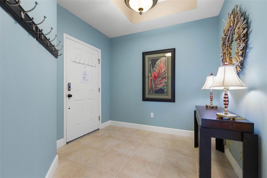An entryway features light blue walls, tile flooring, a console table, and a wall mirror — 1000 CINNAMON BEACH WAY UNIT 941, PALM COAST, FL