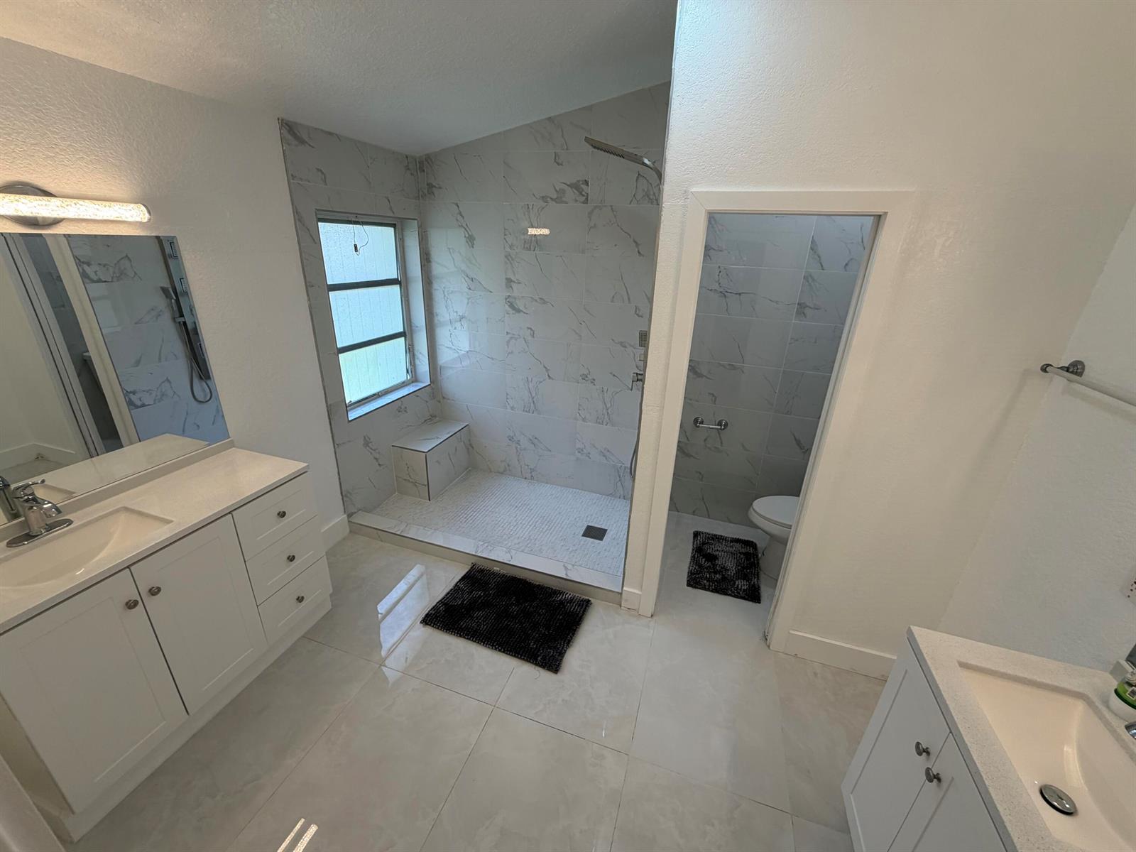 A modern bathroom features a walk-in marble tile shower, dual vanities, and a separate toilet — 9706 Harbour Lake Circle, Boynton Beach FL 33437, BOYNTON BEACH, FL