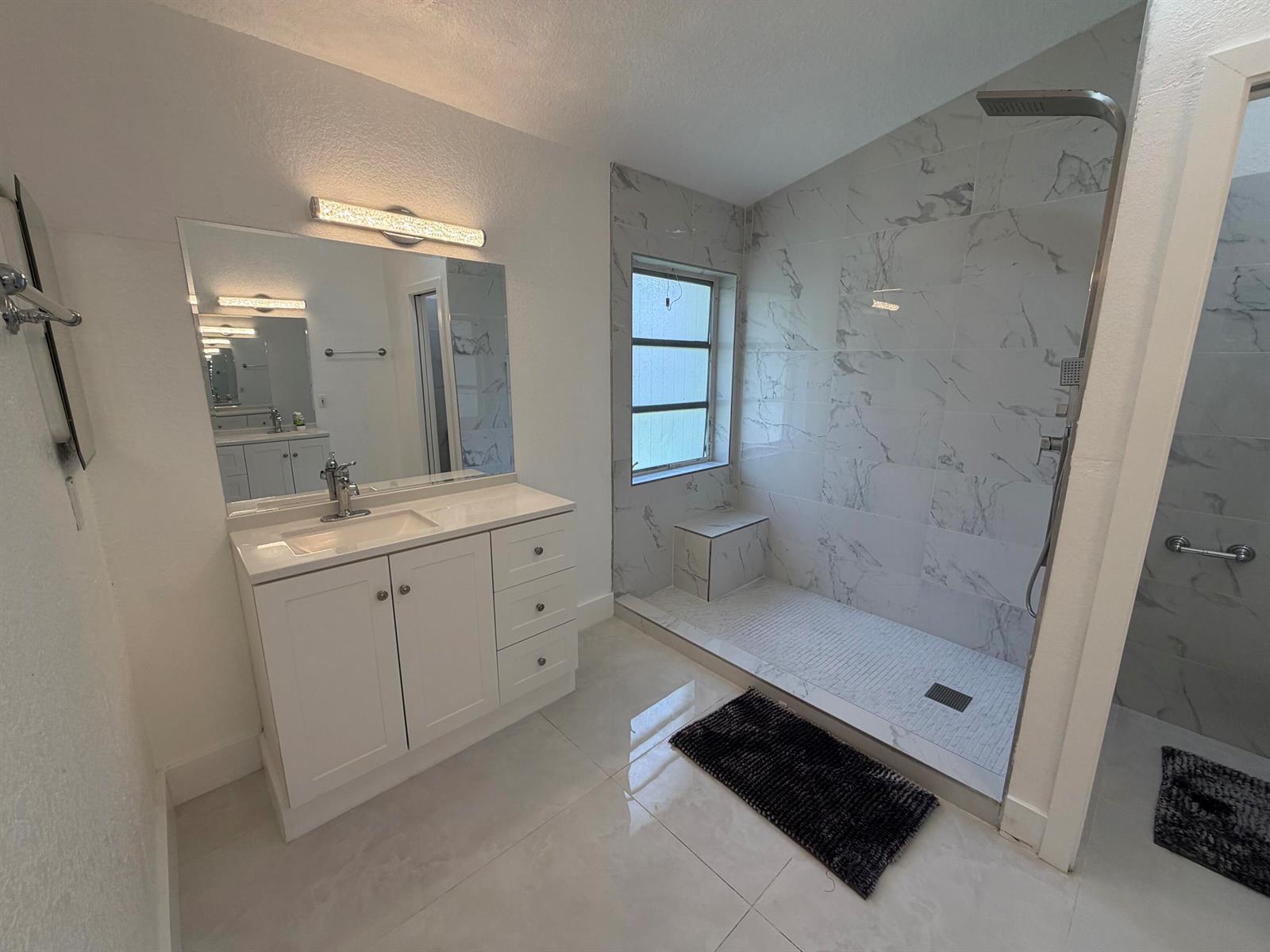 A modern bathroom features a white vanity, a large mirror, and a walk-in marble shower — 9706 Harbour Lake Circle, Boynton Beach FL 33437, BOYNTON BEACH, FL