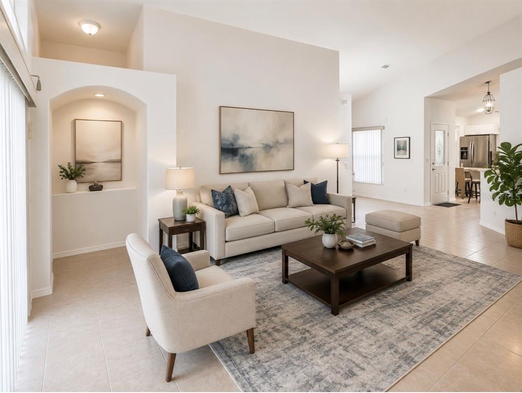 A living room features a beige sofa, an armchair, a coffee table, and an arched alcove — 163 SENECA POINT TRAIL, KISSIMMEE, FL
