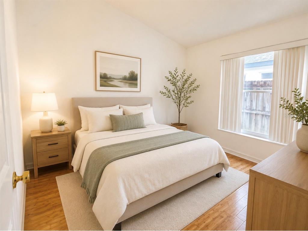 A bedroom features a bed with a green throw, a nightstand, and a window — 163 SENECA POINT TRAIL, KISSIMMEE, FL