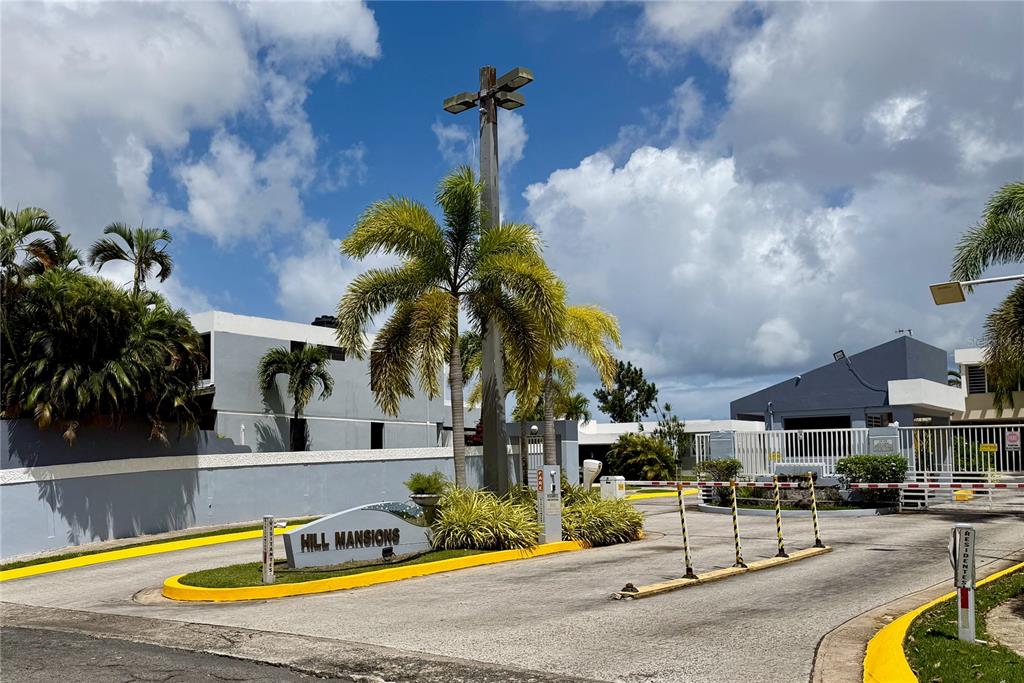 The entrance to Hill Mansions features a gated driveway with palm trees and signage — BF16 65 HILLS MANSIONS, SAN JUAN, PR